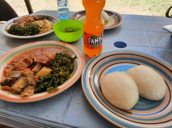 Plates of Zambian food and soft drink bottle on a table