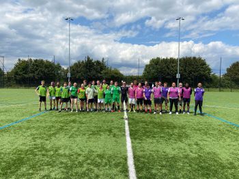 staff and students football teams on the football pitch before the match having a group photo taken