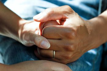 A close up of two people holding hands in a supportive manner