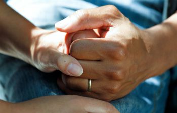 A close up of two people holding hands in a supportive manner
