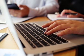 Close up of someone typing on a laptop