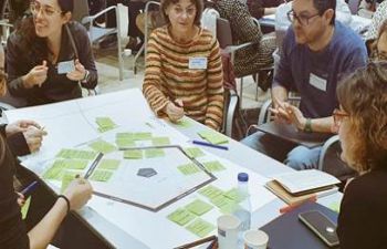 people sat around the table with post-it notes, from universities in Catalonia, using the Lab for the development of social and transformative innovation labs