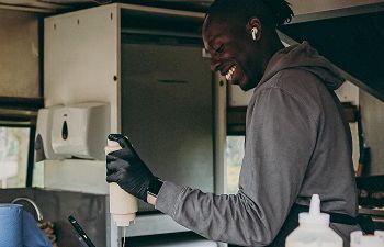 Smiling man serving food from a van