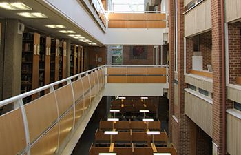 The library atrium. The skylight above and study desks below are visible. Sunlight streams through the windows.