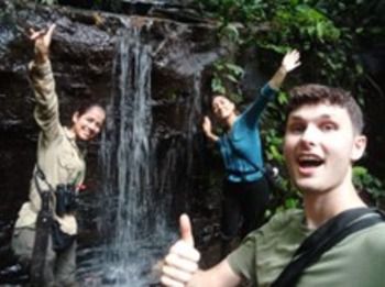 Student Toby Bliss and two team mates posing by a waterfall