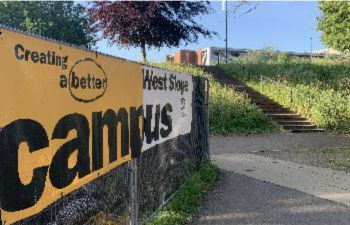 Yellow and white banner reading 'Better Campus' next to a concrete staircase up a hill