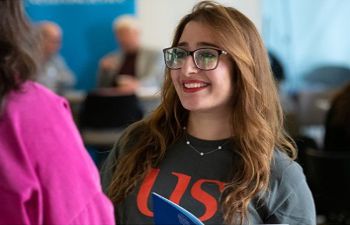 Woman in University of Sussex shirt welcomes new employees