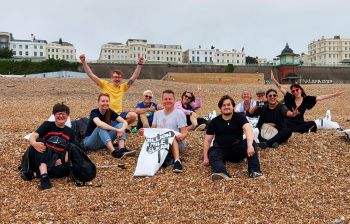 Educational Enhancement department members sit on shingle during charity beach clean