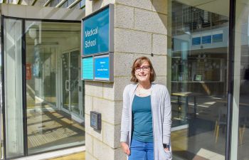 A photo of Eleanor Jayawant in front of the Medical School sign