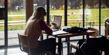 An image of a student studying in a cafe, wearing headphones.