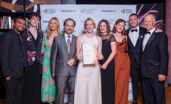 A group of people stood in front of a step and repeat board with a certificate at an awards ceremony in Birmingham