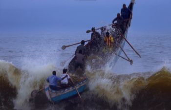 An artisanal boat used for shore seine fishing cuts across shore waves early in the morning on a monsoon day