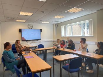 Students share their views and perspectives on sustainable menstrual health and education. They are pictured sitting at tables in a small seminar room together with the lead researchers