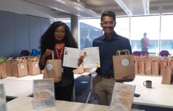 Two members of faculty standing at a table with recipe bags