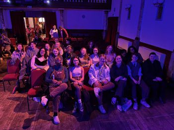 A group of about 20 students sitting in the Stanley Arts theatre, smiling at the camera.