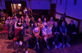 A group of about 20 students sitting in the Stanley Arts theatre, smiling at the camera.