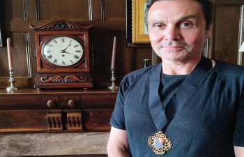 Cllr Matthew Bird - a white man with dark hair standing by the mantelpiece in the Mayor's office