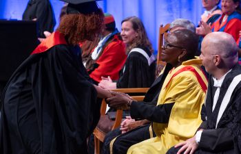 A graduate greeting Baroness Valerie Amos on stage