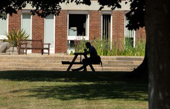 Person sitting on bench outside Arts A building