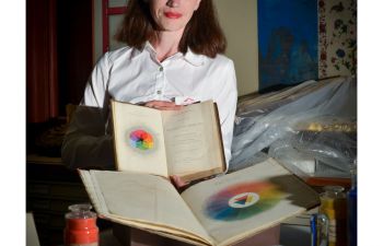 Photograph of Alexandra Loske smiling for camera holding books on colour