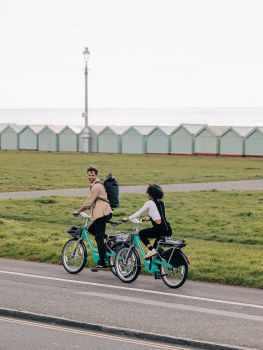 Two people cycling along Brighton & Hove seafront using Beryl bikes.