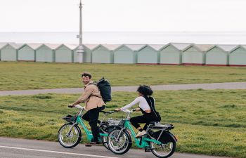 Two people cycling along Brighton & Hove seafront using Beryl bikes.