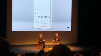 Two individuals, Ros and Joanne, sitting on stage in front of an audience