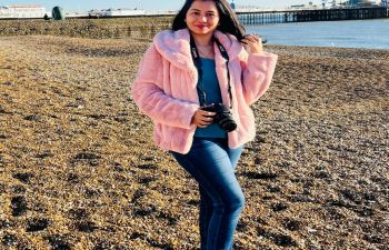 Woman standing on a pebble beach in a pink coat