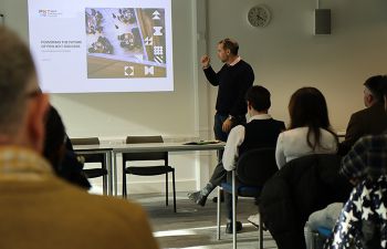 Professor Paul Nightingale looks at presentation screen and addresses seated audience