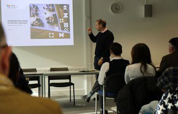 Professor Paul Nightingale looks at presentation screen and addresses seated audience