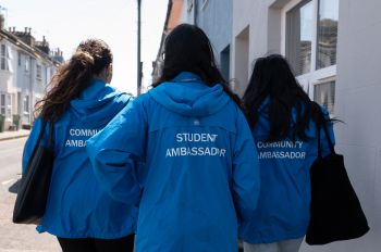 The image shows three community ambassadors walking down a Brighton street