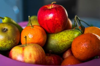 A close-up of a bowl of fruit, including pears, apples and oranges