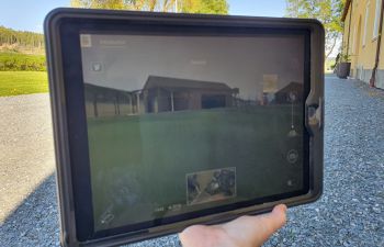 A hand holding a tech table with an image of Falstad concentration camp