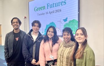 Five Sussex alumni stand side by side in front of a large digital screen that reads 'Green Futures'