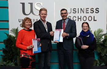 Merrill Jones, Dr René Moolenaar, Prof Steven McGuire, Caroline Barrow holding a printed copy of the Carbon Literacy training report