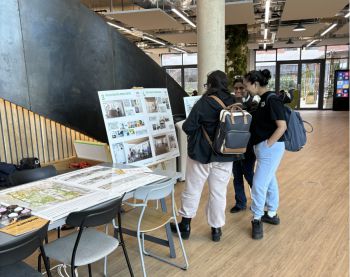 2 students look at an easel with a poster board showing architectural images