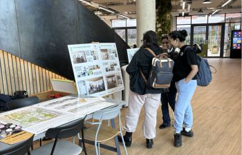 2 students look at an easel with a poster board showing architectural images