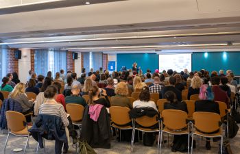 People sat on chairs in a room watching a lecture at the HRP conference