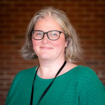 A photo of Dr Claire Potter wearing a green top and black glasses