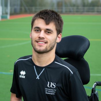 Louis Saunders smiling with a sports pitch behind him