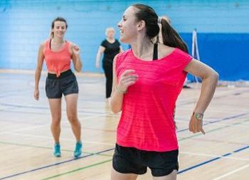Woman in red top exercising in a sports hall