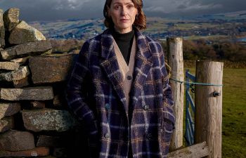 Suranne Jones standing in front of a rocky landscape