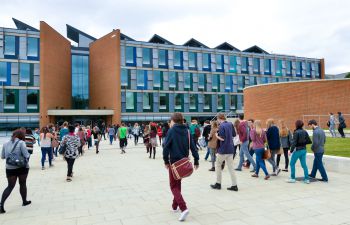 Image of business school exterior with students walking towards the building