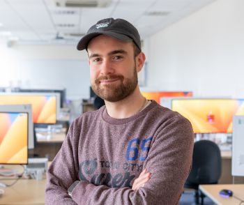 Ben Foard, Paxton Scholar wearing a baseball cap, smiling and standing in front of computer monitors