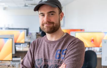 Ben Foard, Paxton Scholar wearing a baseball cap, smiling and standing in front of computer monitors