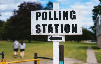 A white wooden sign post with black painted letters reading 'Polling station'