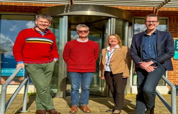 A photo of four of the SCRC team stood outside the research building on the steps smiling