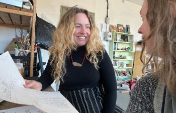 Rachael sat at table with artist Ottilie Hainsworth in studio, discussing story mapping workshop ideas