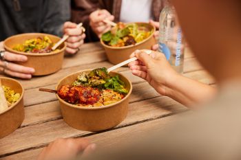 A delicious looking healthy bowl of food that includes chicken skewers and broccoli