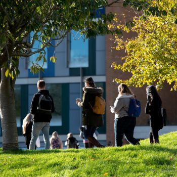 Three students walking on the University of Sussex campus